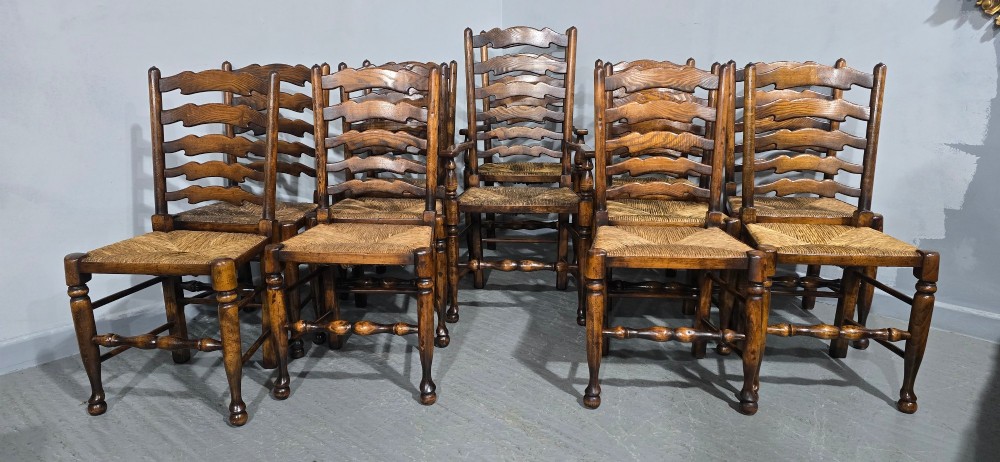 A set of twelve dark oak ladder back dining chairs featuring woven rush seats, shaped horizontal back slats, and turned front legs. View VII