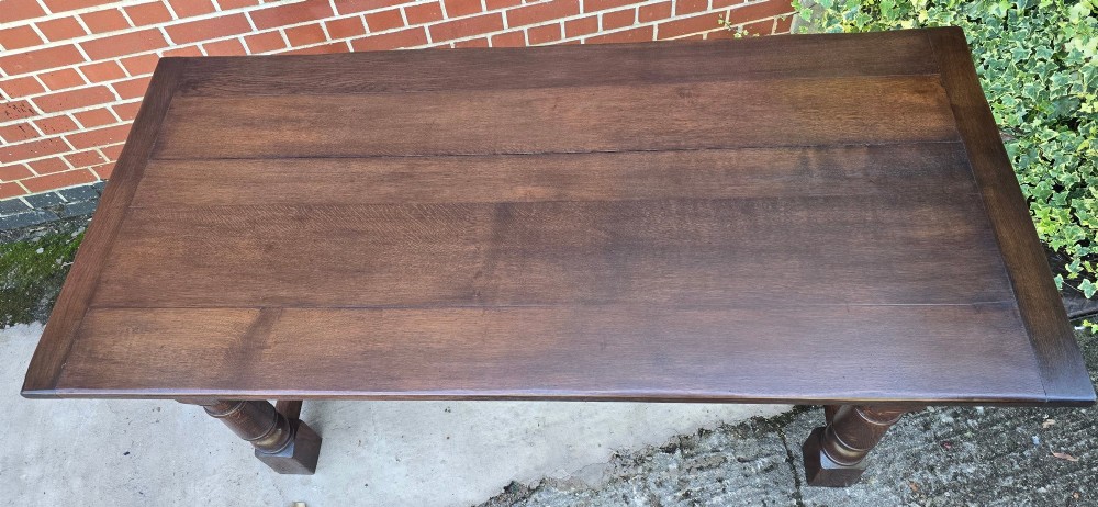 A solid dark oak refectory dining table with a plank top, stout turned legs, and an H-stretcher base. View X
