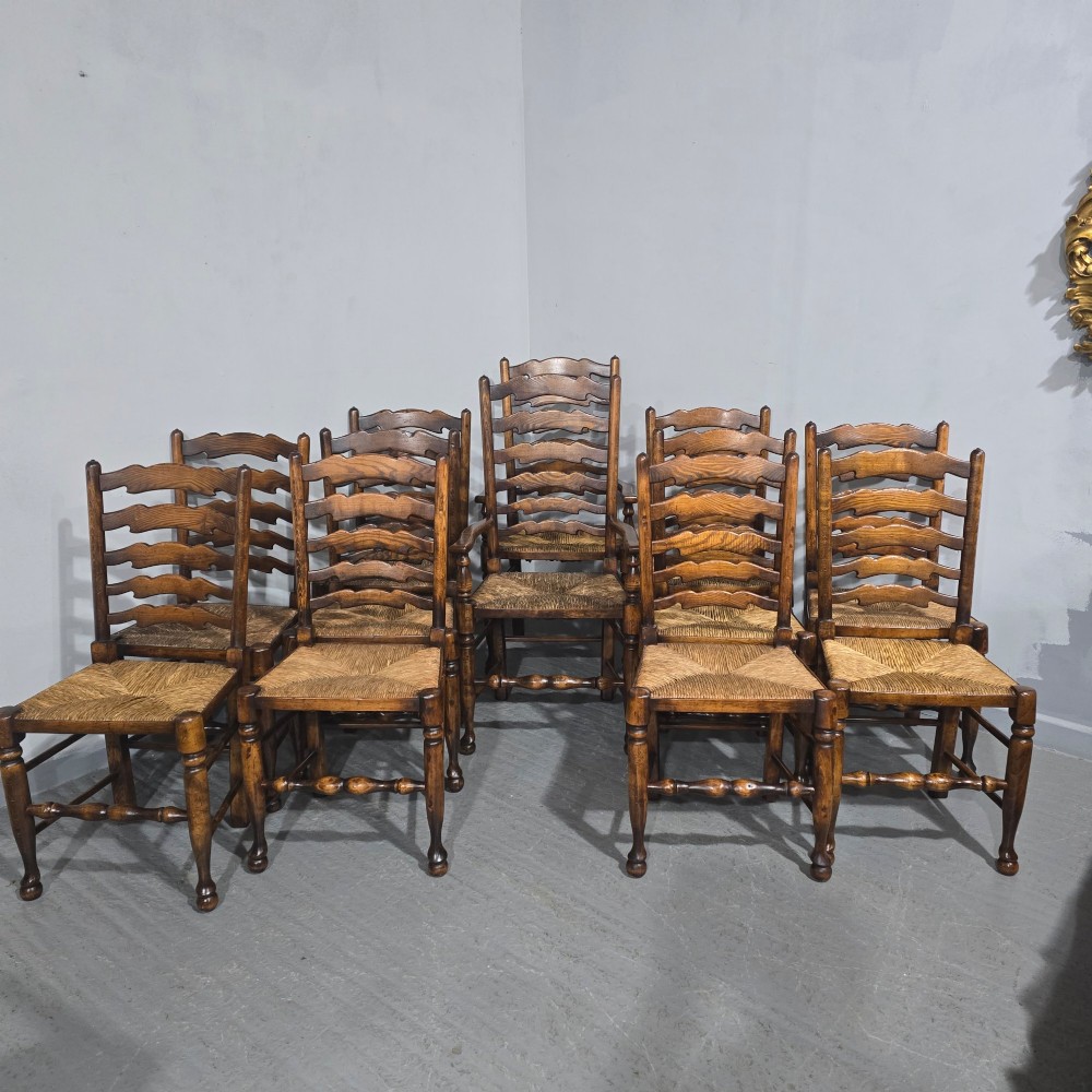 A set of twelve oak dining chairs featuring shaped ladder back slats, natural rush seats, and turned front legs. View II