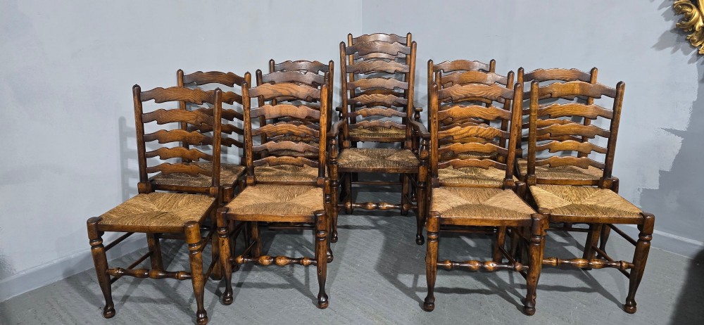 A set of twelve oak dining chairs featuring shaped ladder back slats, natural rush seats, and turned front legs. View III