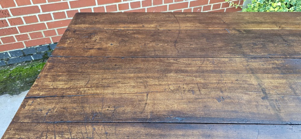 A rectangular rustic oak dining table featuring a frieze drawer with a wooden knob and four square tapered legs. View IX