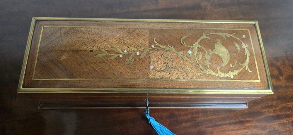 A rectangular antique French wooden glove box with floral marquetry inlay on the lid and a blue tassel attached to the key. View III