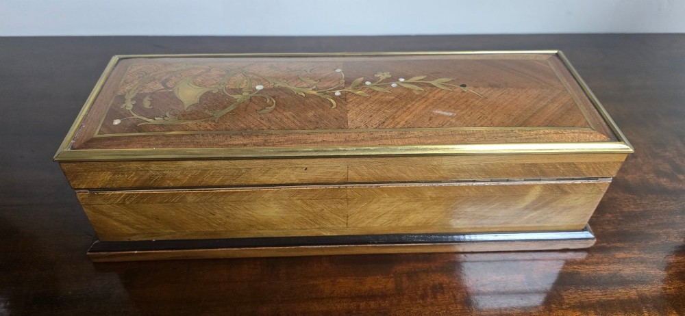 A rectangular antique French wooden glove box with floral marquetry inlay on the lid and a blue tassel attached to the key. View V