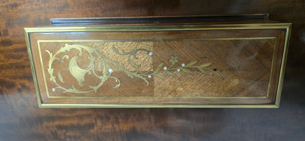 A rectangular antique French wooden glove box with floral marquetry inlay on the lid and a blue tassel attached to the key. View X