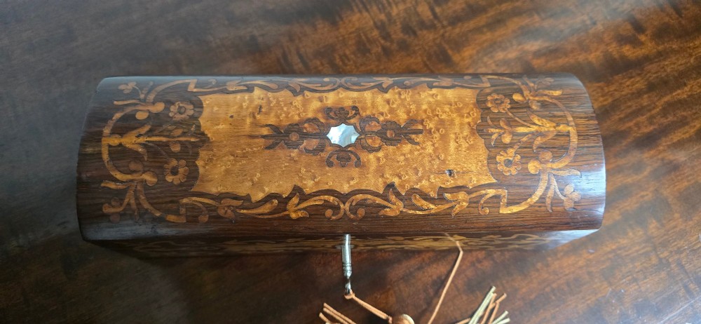 An antique dark wood rectangular glove box featuring foliate marquetry inlay, a curved lid, a key with a silk tassel, and a mother-of-pearl escutcheon. View IV