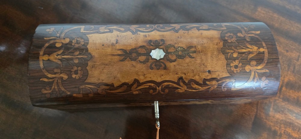 An antique dark wood rectangular glove box featuring foliate marquetry inlay, a curved lid, a key with a silk tassel, and a mother-of-pearl escutcheon. View VI