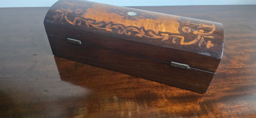 An antique dark wood rectangular glove box featuring foliate marquetry inlay, a curved lid, a key with a silk tassel, and a mother-of-pearl escutcheon. View VII