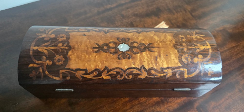 An antique dark wood rectangular glove box featuring foliate marquetry inlay, a curved lid, a key with a silk tassel, and a mother-of-pearl escutcheon. View VIII