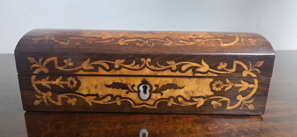 An antique dark wood rectangular glove box featuring foliate marquetry inlay, a curved lid, a key with a silk tassel, and a mother-of-pearl escutcheon. View XII