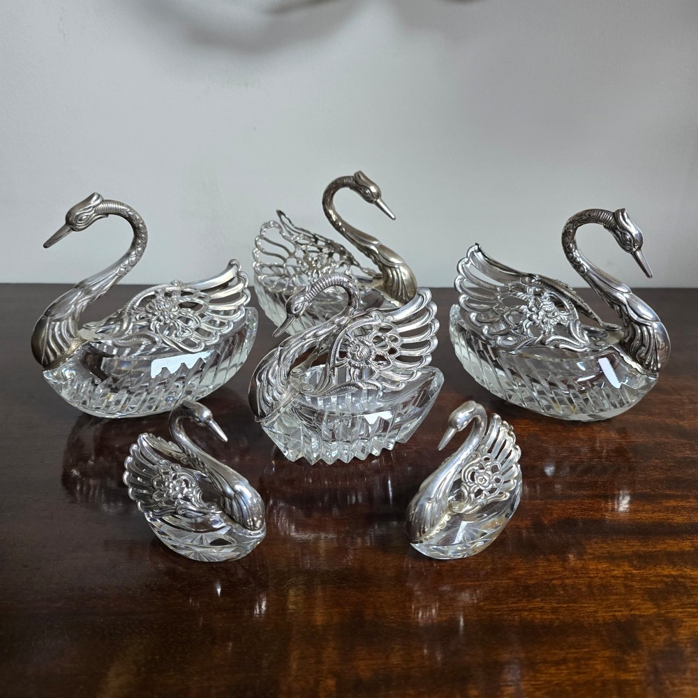 A group of cut glass open salt cellars shaped like swans with silver heads and detailed pierced silver wings. View II