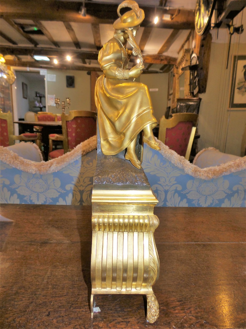 A mid-19th-century French gilt bronze and patinated bronze mantel clock featuring a seated female figure holding a fan atop an ornate sculpted base. View II