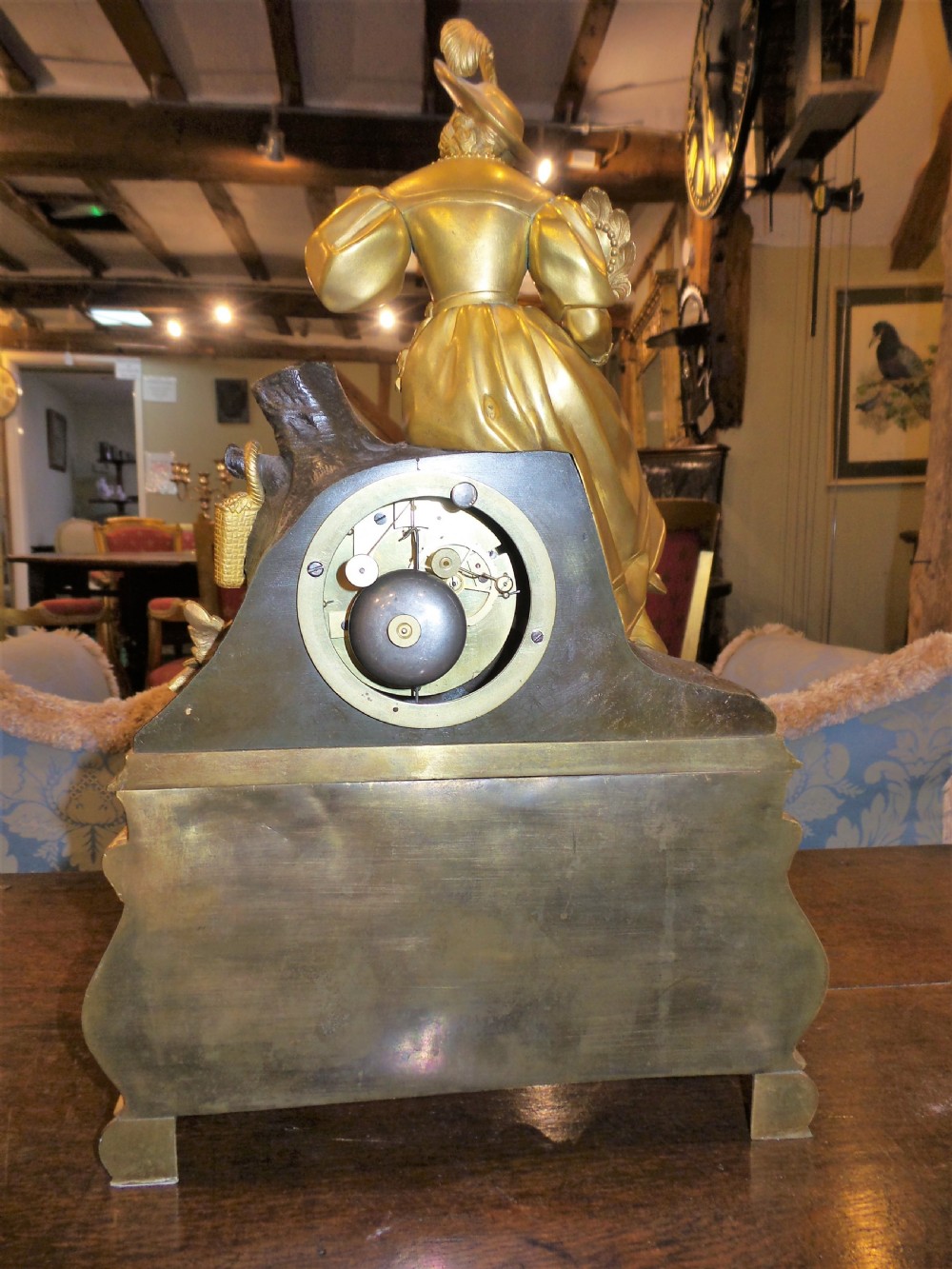 A mid-19th-century French gilt bronze and patinated bronze mantel clock featuring a seated female figure holding a fan atop an ornate sculpted base. View III