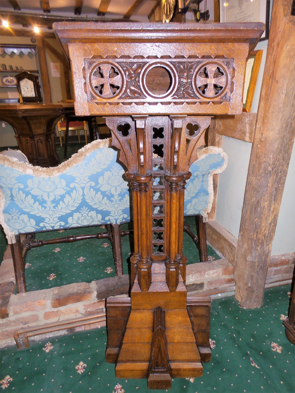 A nineteenth-century carved dark oak Gothic Revival lectern featuring a sloped reading surface, pierced tracery shaft, and stepped base. View V