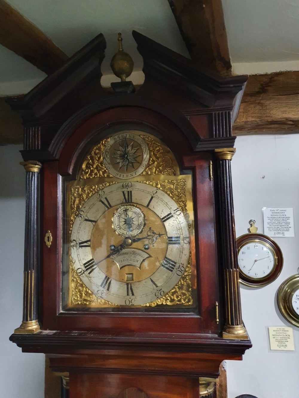A Georgian flame mahogany eight-day longcase clock featuring a pedimented hood with fluted columns, a brass dial with spandrels, and a tall panelled case. View IV