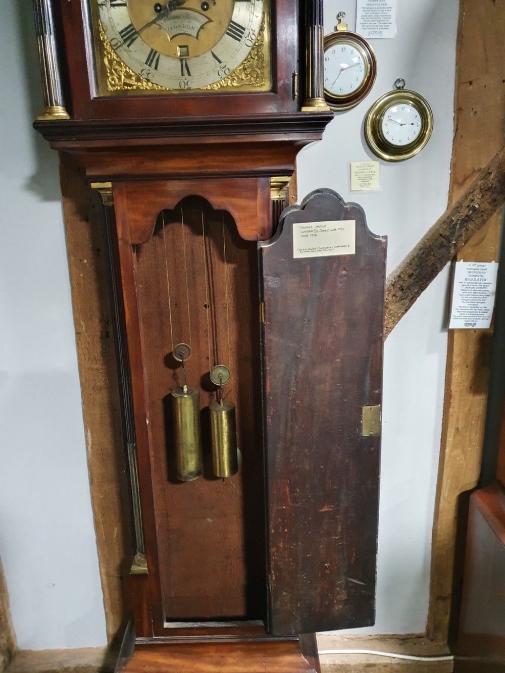 A Georgian flame mahogany eight-day longcase clock featuring a pedimented hood with fluted columns, a brass dial with spandrels, and a tall panelled case. View VI