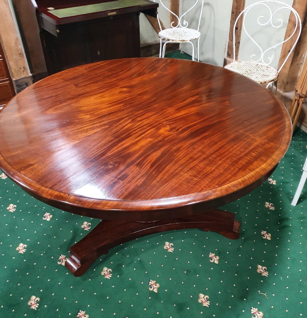A 19th-century circular flame mahogany breakfast table featuring a polished top supported by a central pedestal base.