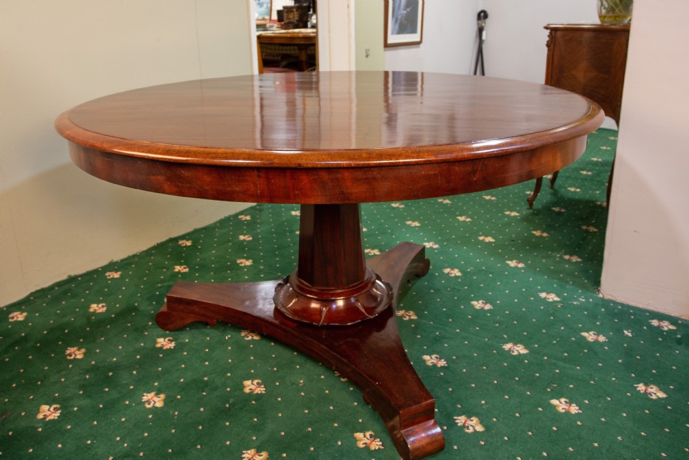 A 19th-century circular flame mahogany breakfast table featuring a polished top supported by a central pedestal base. View VII