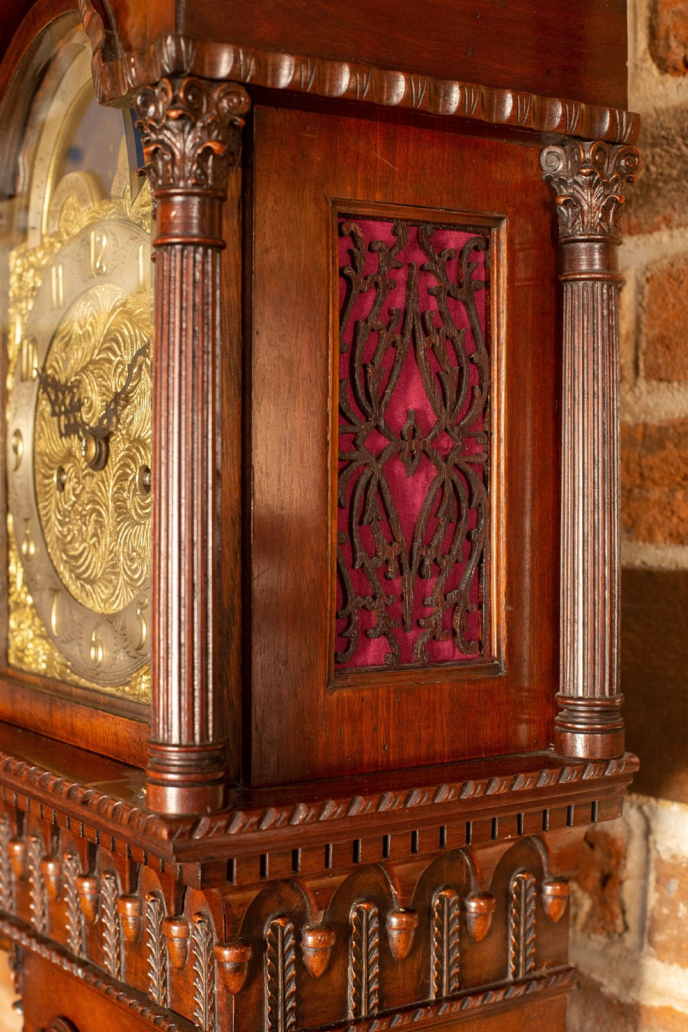 An Edwardian miniature mahogany longcase clock featuring a carved swan-neck pediment, brass moon phase dial, and glass trunk door revealing brass weights. View II