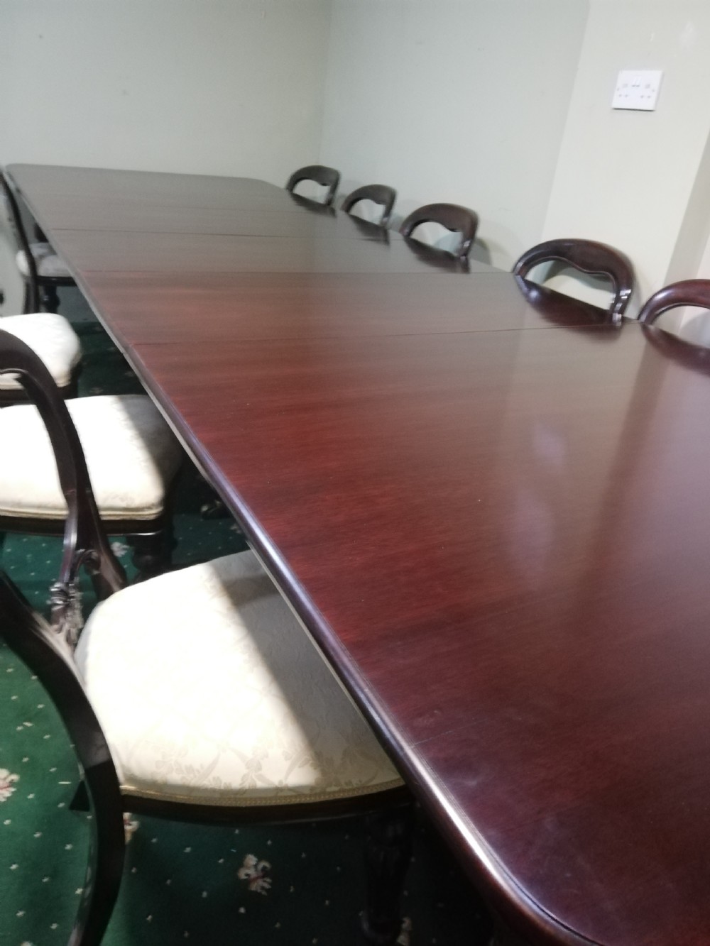 A long dark mahogany extending dining table surrounded by matching balloon back chairs with light fabric upholstered seats. View V
