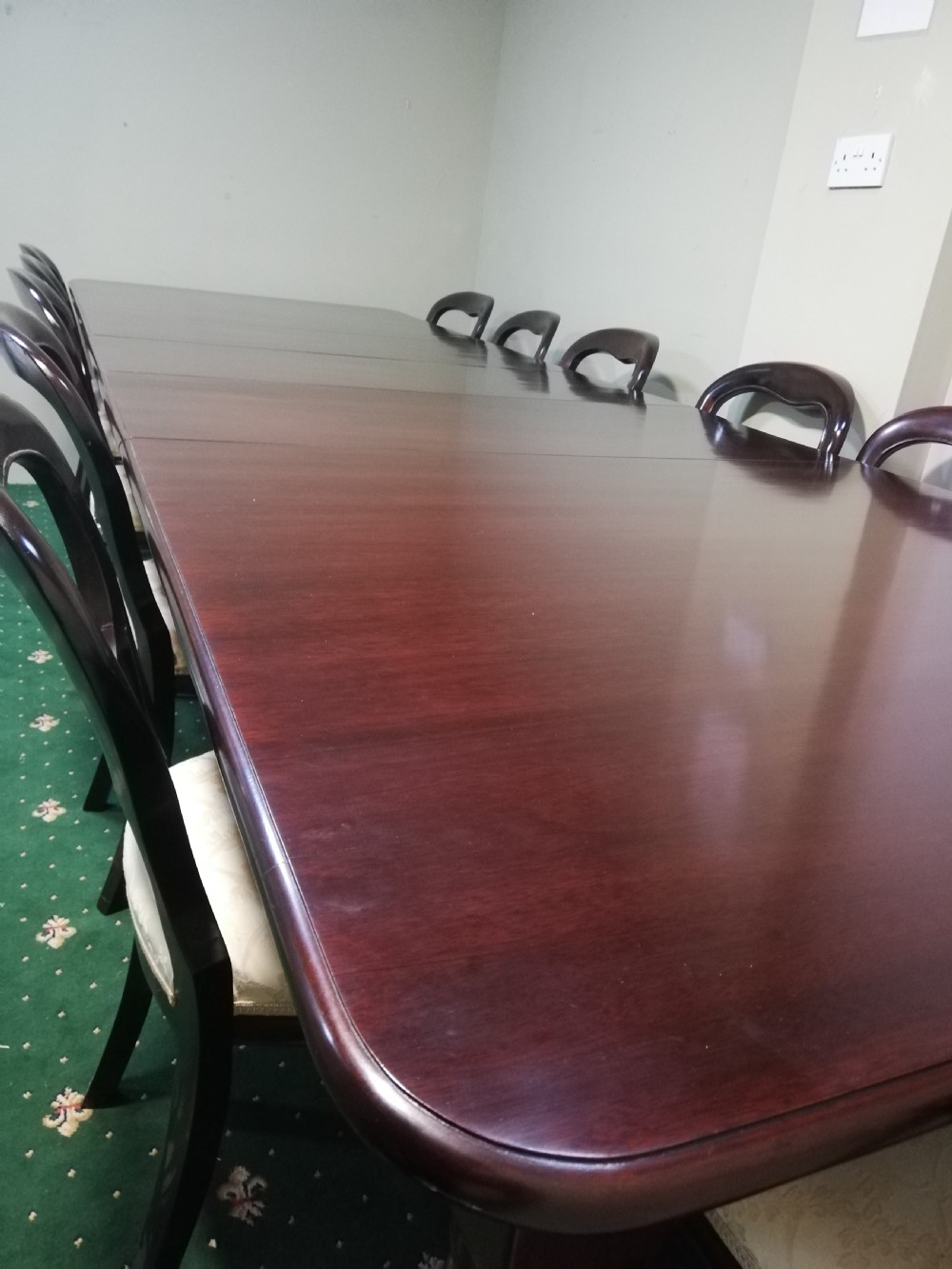 A long dark mahogany extending dining table surrounded by matching balloon back chairs with light fabric upholstered seats. View VI