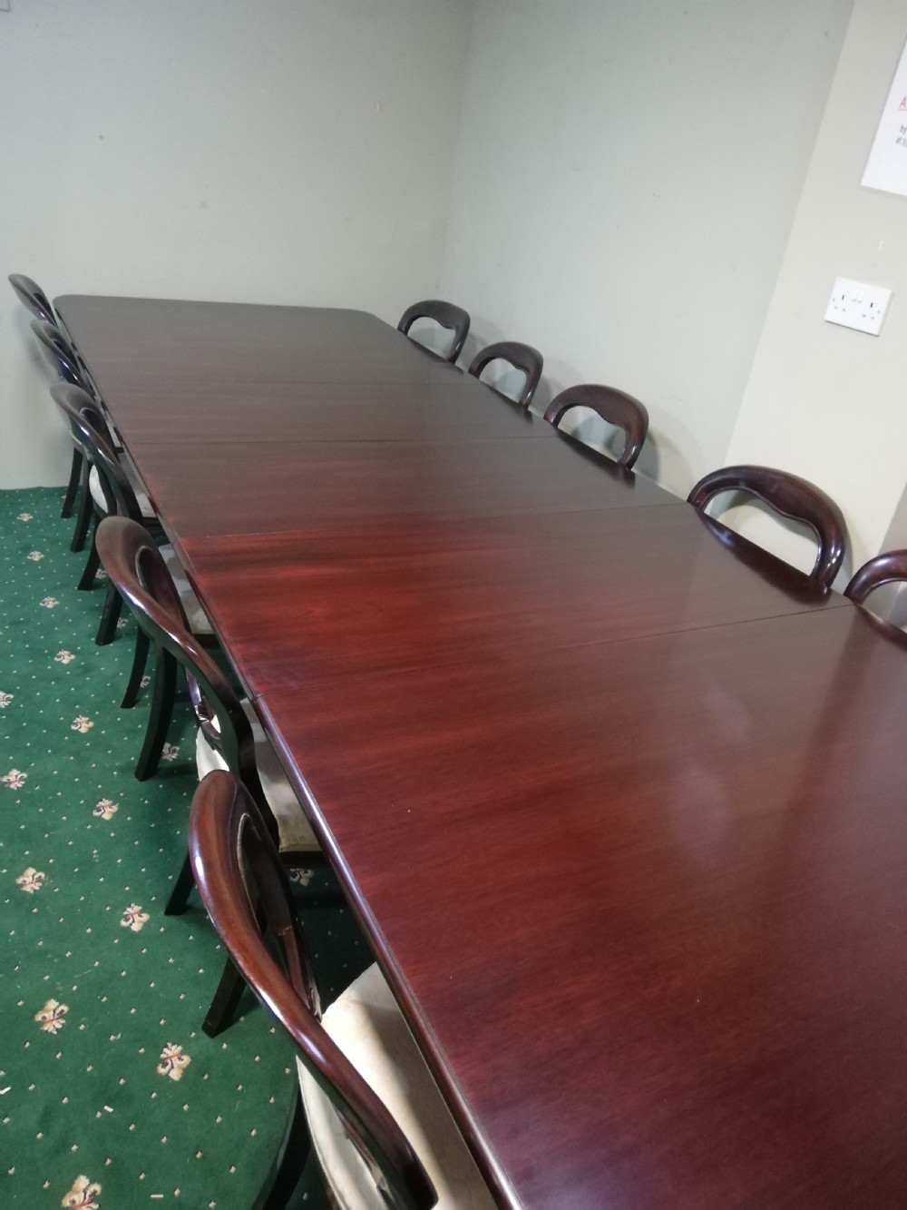 A long dark mahogany extending dining table surrounded by matching balloon back chairs with light fabric upholstered seats. View VII