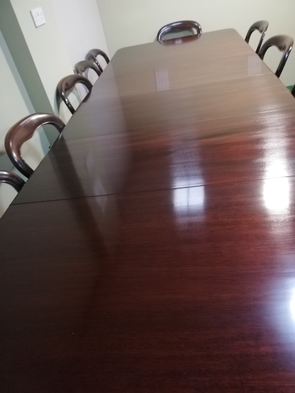 A long dark mahogany extending dining table surrounded by matching balloon back chairs with light fabric upholstered seats. View IX