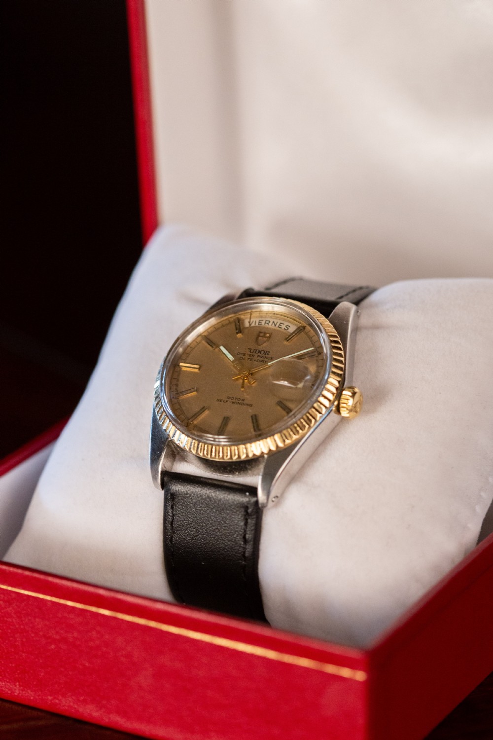 A vintage Tudor Oyster Prince Date+Day wristwatch with a gold fluted bezel, champagne dial, and black leather strap. View II