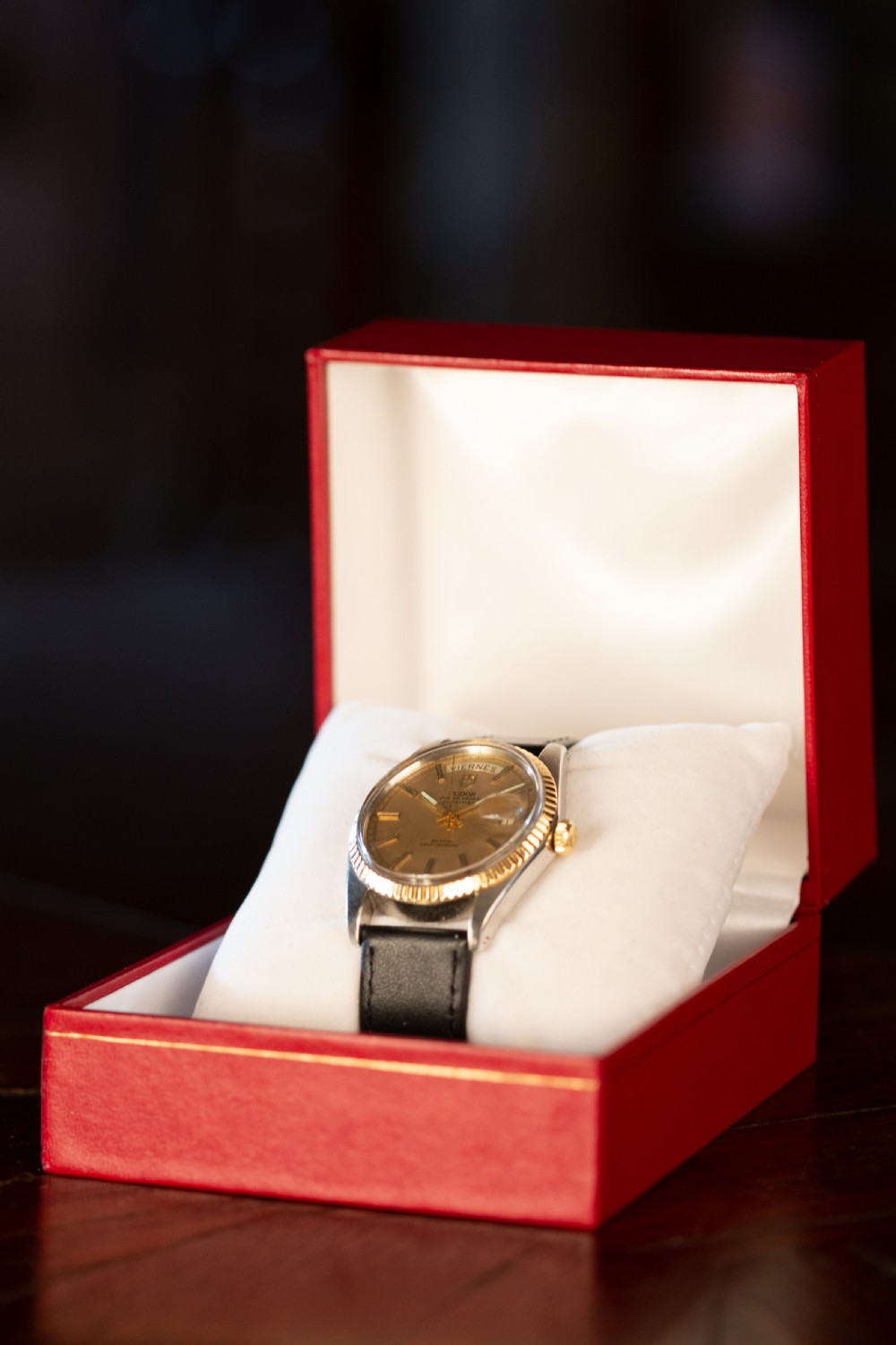A vintage Tudor Oyster Prince Date+Day wristwatch with a gold fluted bezel, champagne dial, and black leather strap. View III