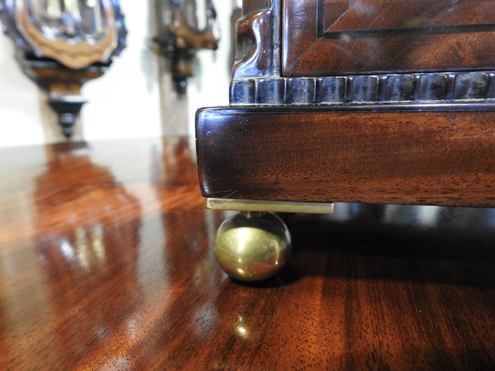 An antique Regency flame mahogany bracket clock featuring a gabled top, a silvered dial signed Vulliamy London, and brass ball feet. View IX