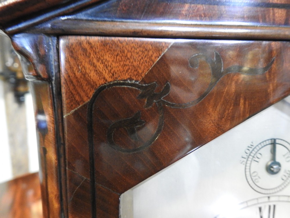 An antique Regency flame mahogany bracket clock featuring a gabled top, a silvered dial signed Vulliamy London, and brass ball feet. View X