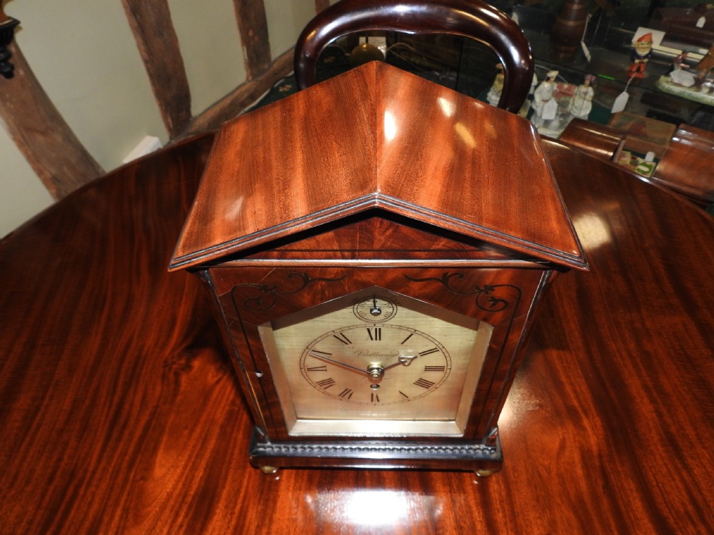 An antique Regency flame mahogany bracket clock featuring a gabled top, a silvered dial signed Vulliamy London, and brass ball feet. View XII