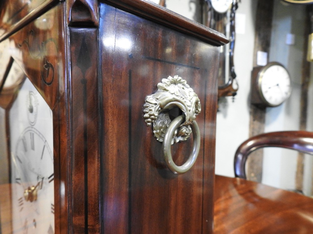 An antique Regency flame mahogany bracket clock featuring a gabled top, a silvered dial signed Vulliamy London, and brass ball feet. View XIII