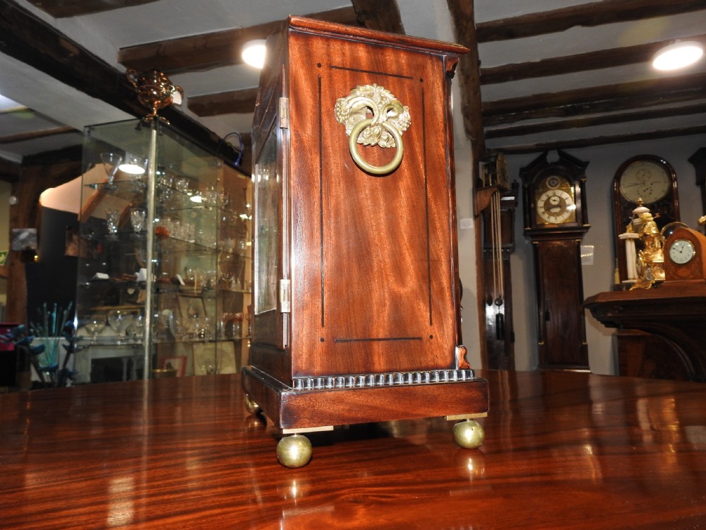 An antique Regency flame mahogany bracket clock featuring a gabled top, a silvered dial signed Vulliamy London, and brass ball feet. View XV