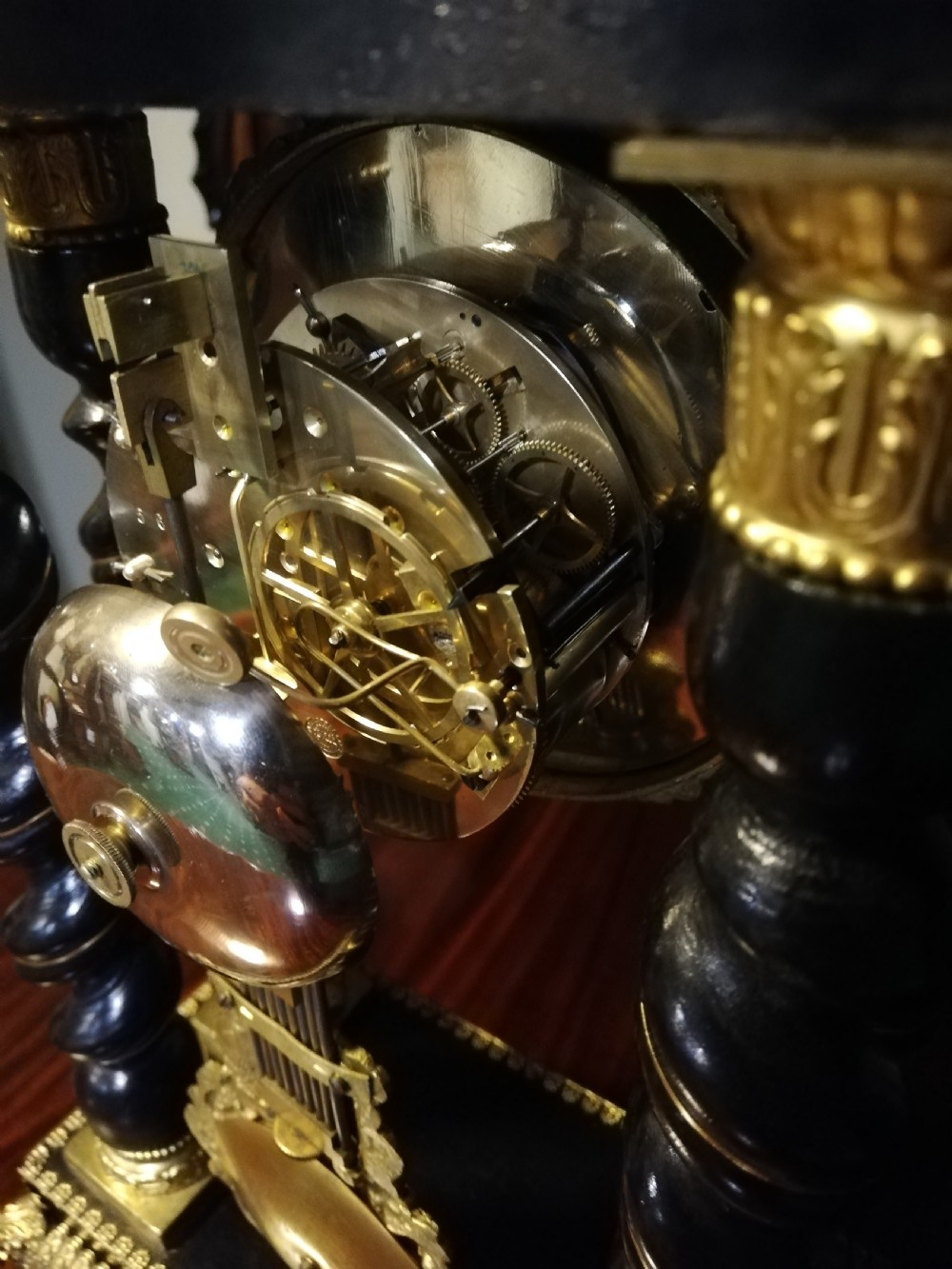 A 19th-century French portico mantel clock featuring ebonised barley twist columns, gilt bronze mounts, stone inlay, and an original glass cloche. View XIII