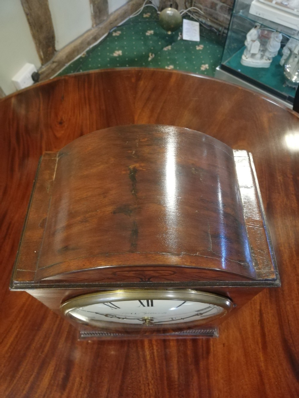 An antique mahogany bracket clock featuring an arched top, inlaid woodwork, a white dial with Roman numerals signed W. Clark London, and brass bun feet. View III
