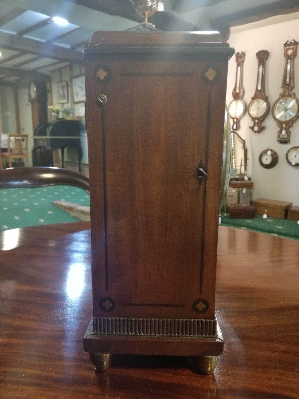 An antique mahogany bracket clock featuring an arched top, inlaid woodwork, a white dial with Roman numerals signed W. Clark London, and brass bun feet. View IV