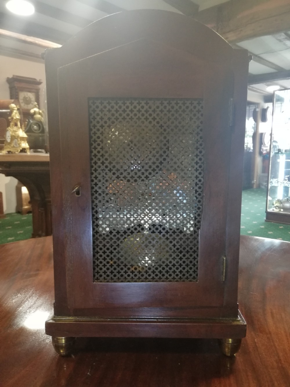 An antique mahogany bracket clock featuring an arched top, inlaid woodwork, a white dial with Roman numerals signed W. Clark London, and brass bun feet. View V