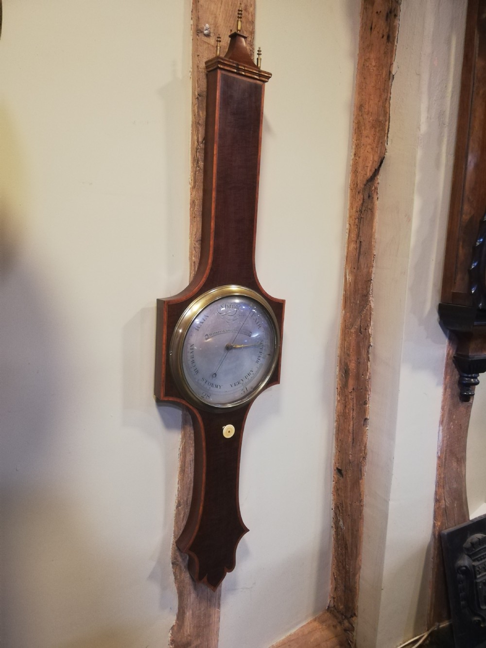 An antique Georgian mahogany wheel barometer featuring a silvered dial with brass bezel, dark wooden casing with inlay, and a pediment top. View VII