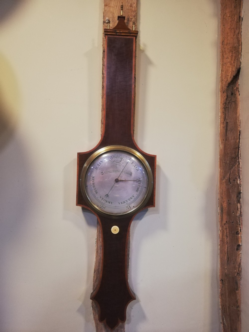 An antique Georgian mahogany wheel barometer featuring a silvered dial with brass bezel, dark wooden casing with inlay, and a pediment top.