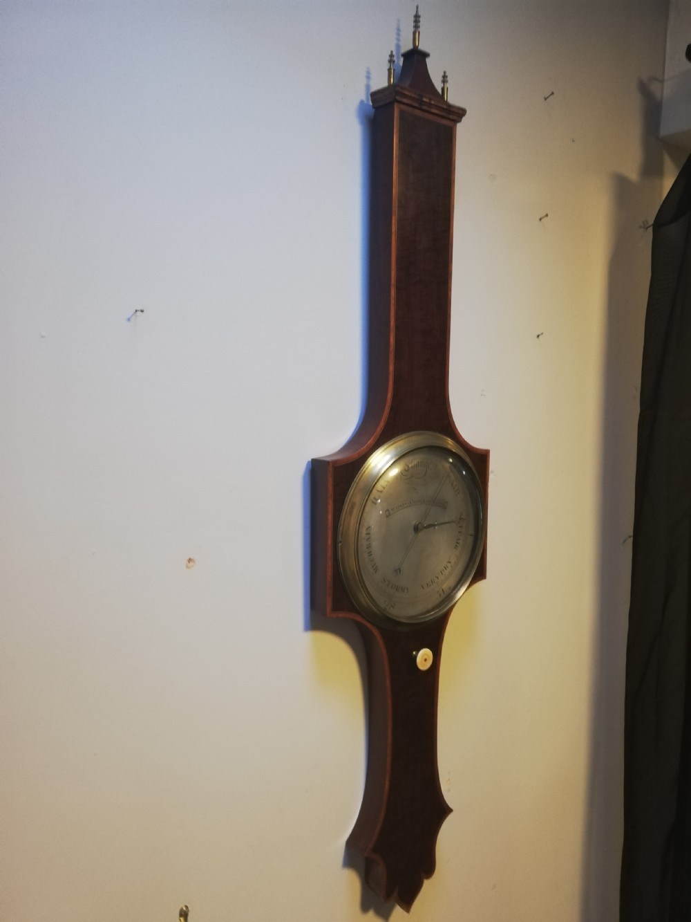 An antique Georgian mahogany wheel barometer featuring a silvered dial with brass bezel, dark wooden casing with inlay, and a pediment top. View X