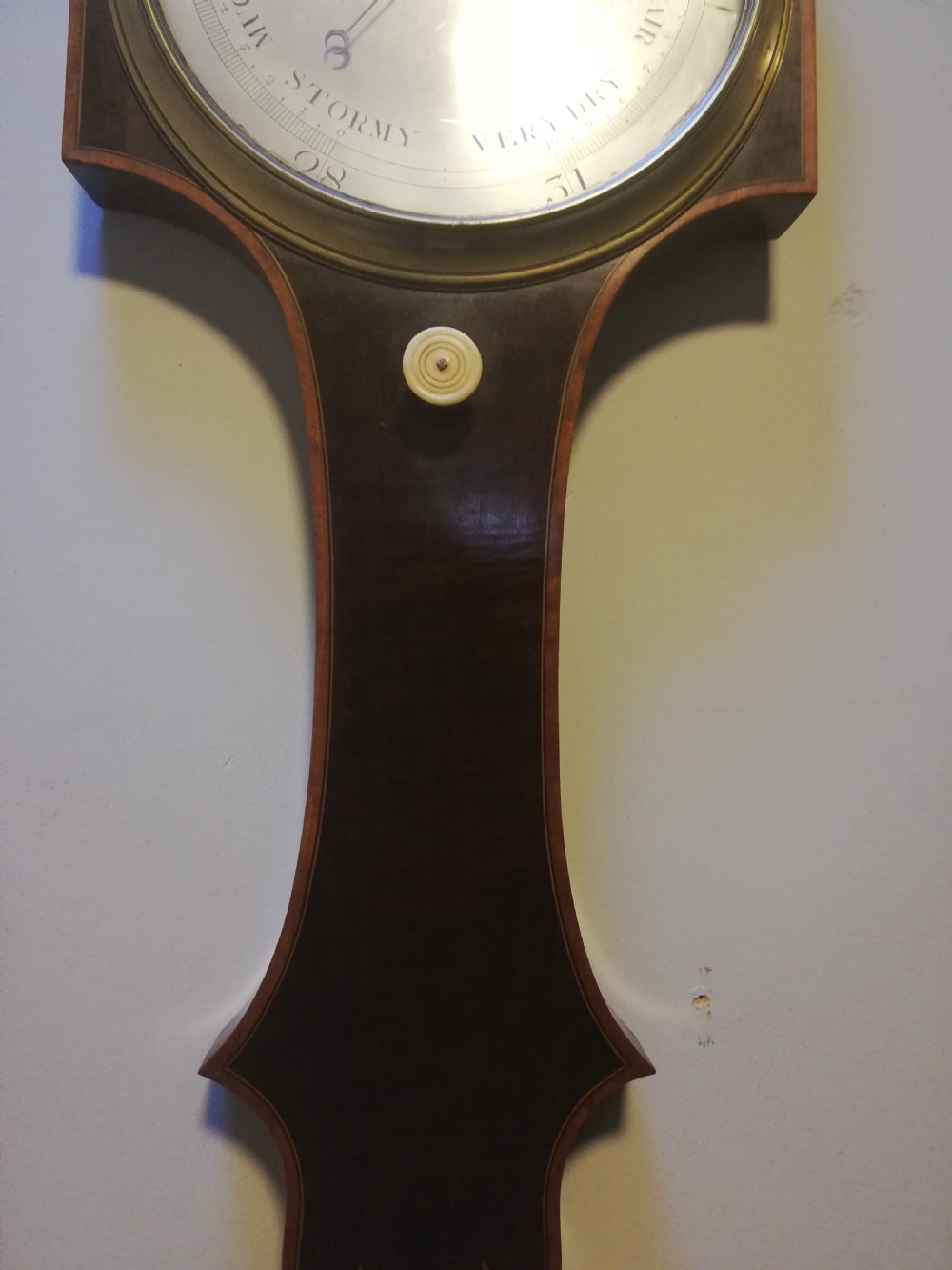 An antique Georgian mahogany wheel barometer featuring a silvered dial with brass bezel, dark wooden casing with inlay, and a pediment top. View XXI