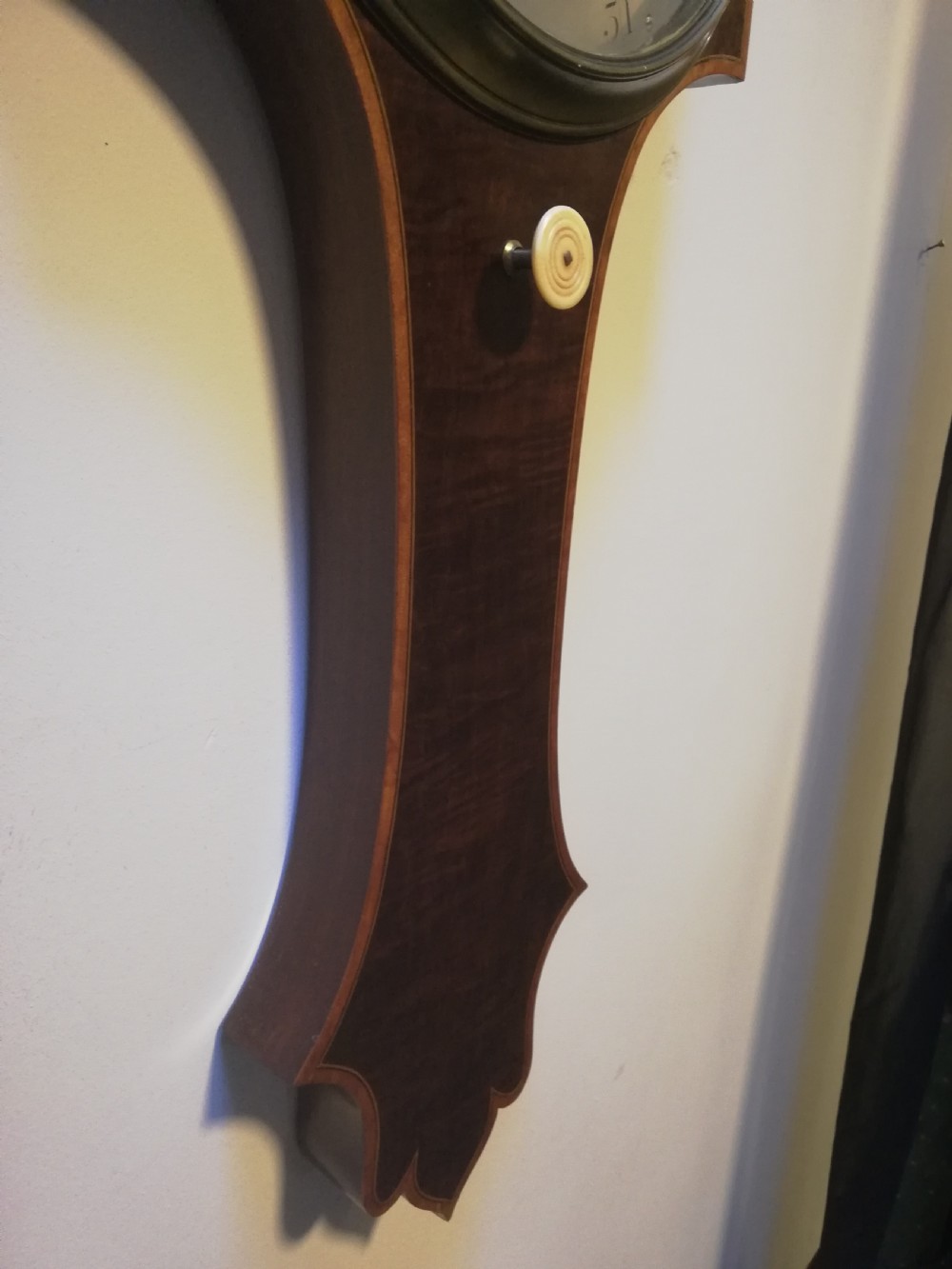 An antique Georgian mahogany wheel barometer featuring a silvered dial with brass bezel, dark wooden casing with inlay, and a pediment top. View XXIII