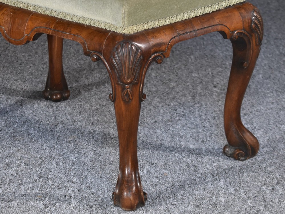 A rectangular George I style walnut stool featuring carved cabriole legs with shell motifs and a sage green velvet seat. View II
