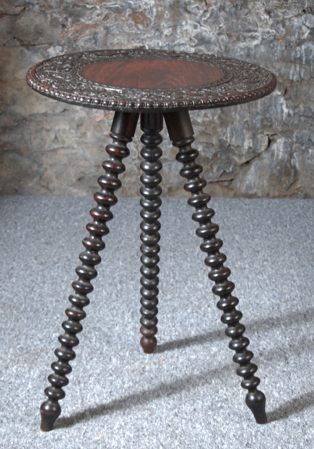 A 19th-century Burmese dark padouk side table with a circular carved top and three bobbin-turned legs forming a tripod base.