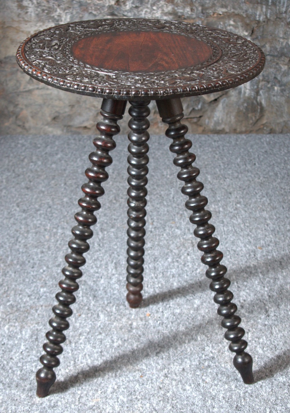 A 19th-century Burmese dark padouk side table with a circular carved top and three bobbin-turned legs forming a tripod base. View II