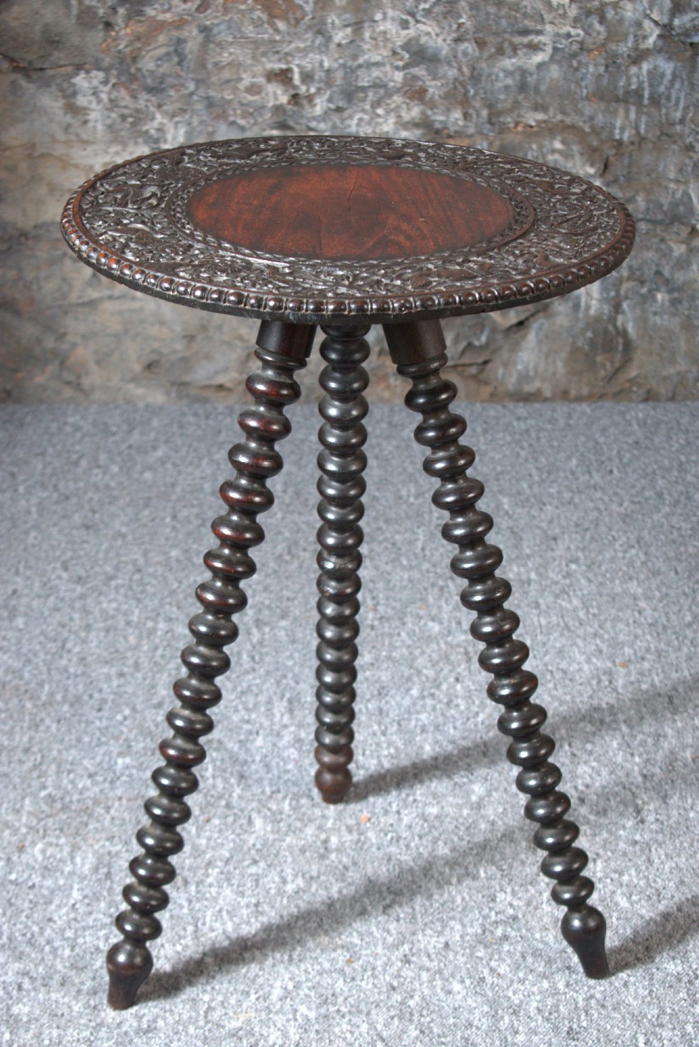 A 19th-century Burmese dark padouk side table with a circular carved top and three bobbin-turned legs forming a tripod base. View III