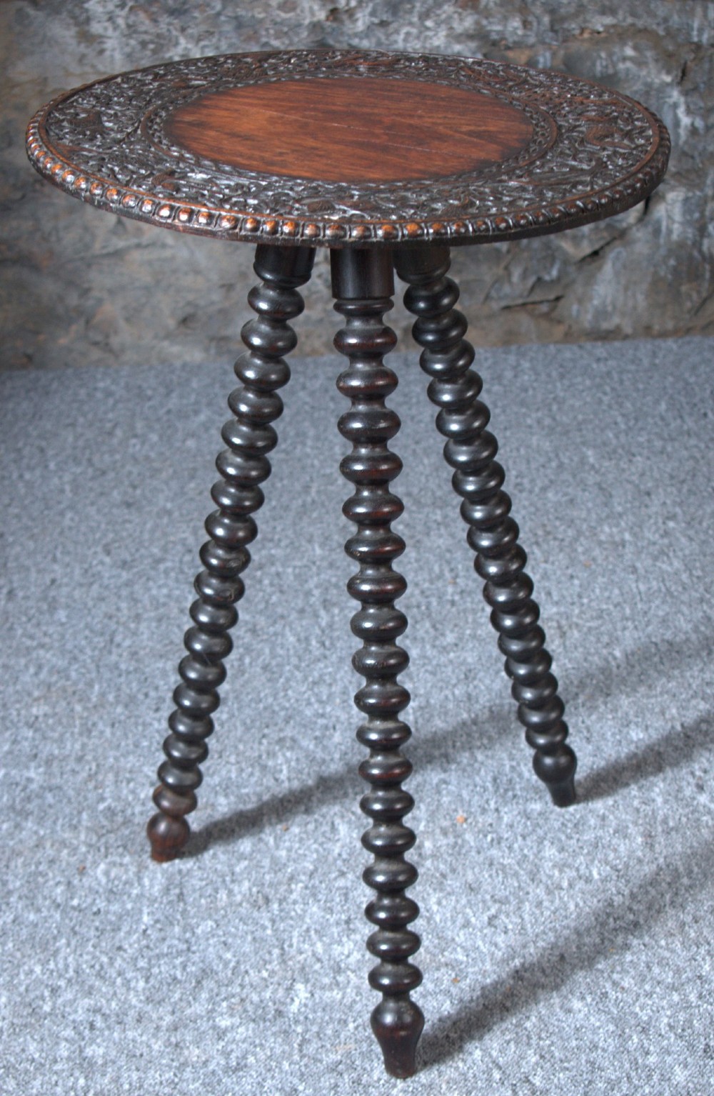 A 19th-century Burmese dark padouk side table with a circular carved top and three bobbin-turned legs forming a tripod base. View IV