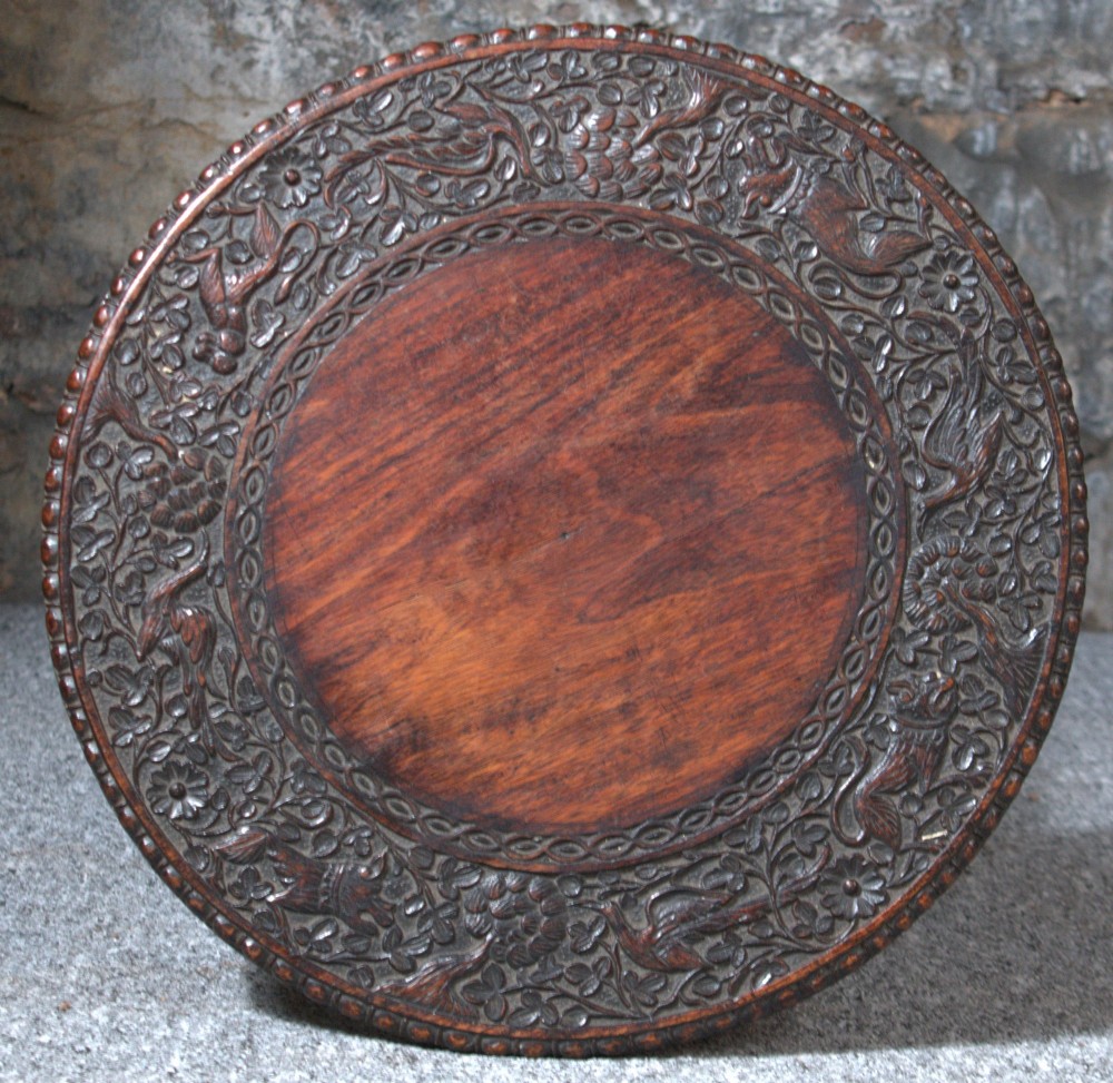 A 19th-century Burmese dark padouk side table with a circular carved top and three bobbin-turned legs forming a tripod base. View V