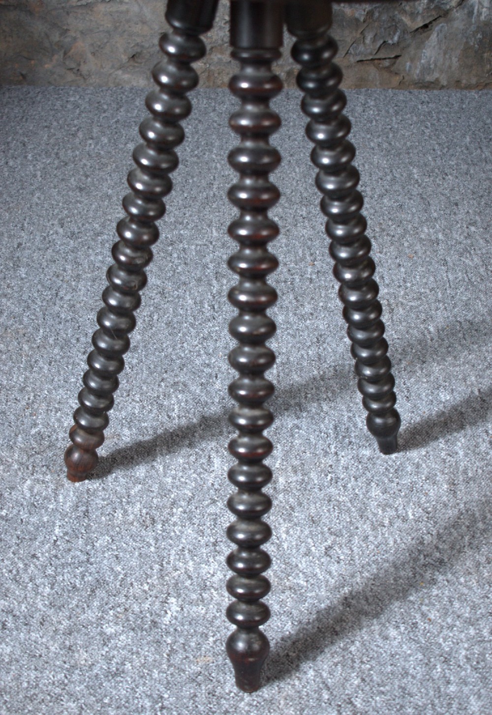 A 19th-century Burmese dark padouk side table with a circular carved top and three bobbin-turned legs forming a tripod base. View VI