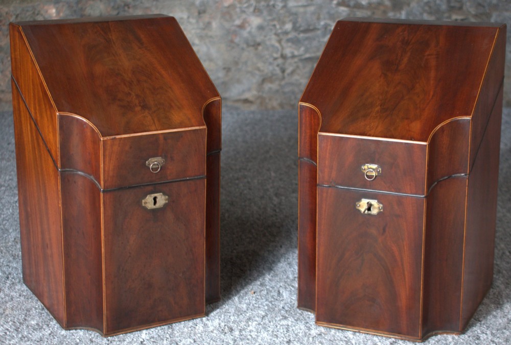 A pair of late eighteenth-century George III mahogany knife boxes featuring sloped lids, serpentine fronts, and brass ring fittings.